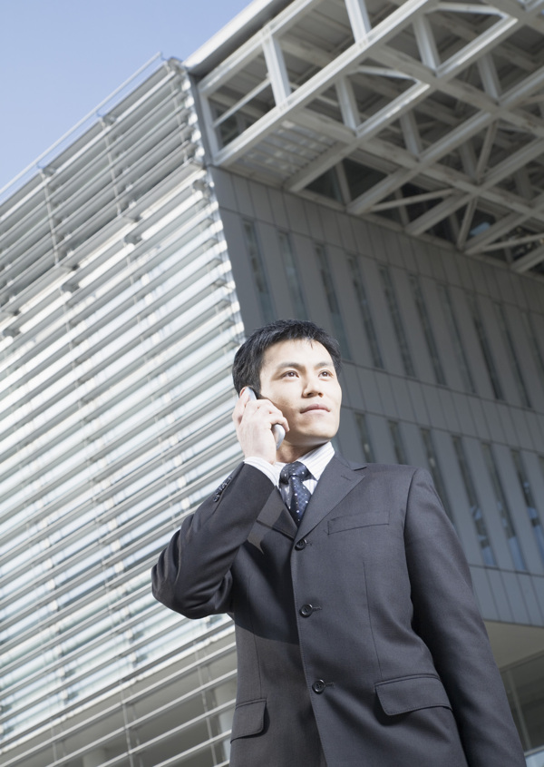 站在大厦前讲电话的商务男人图片