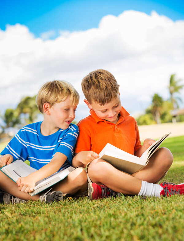 草地上看书的两个外国小男孩图片