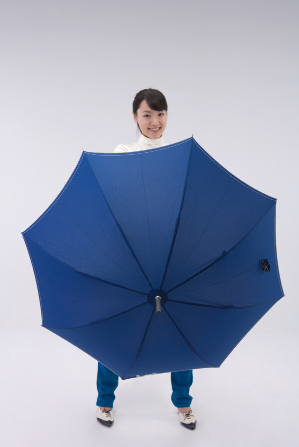 撑起蓝色雨伞的开心女孩图片