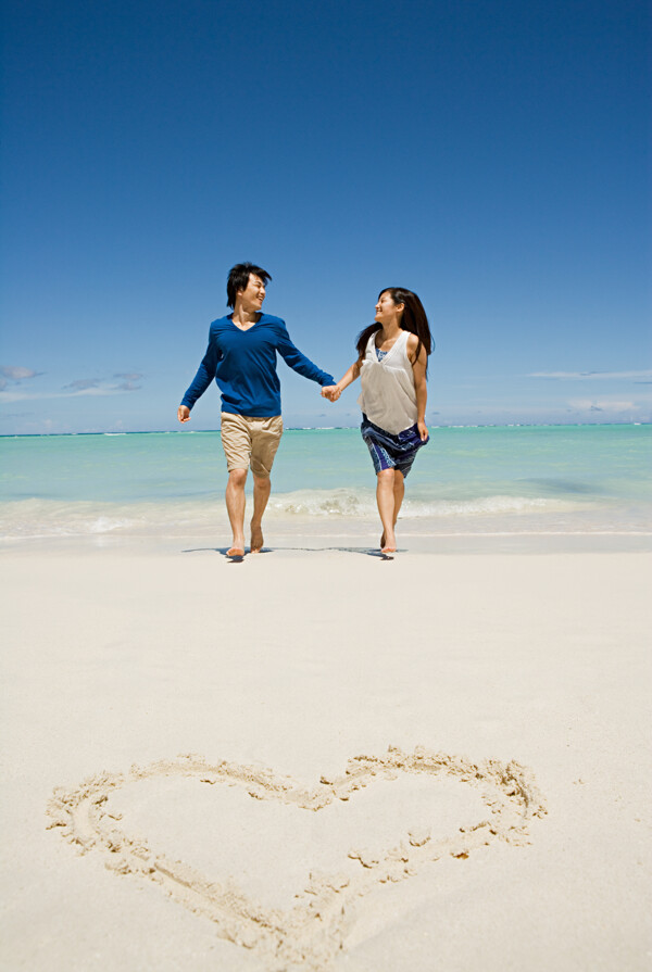 牵手走在沙滩上的快乐情侣图片