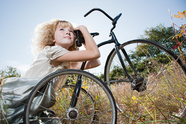 草丛中趴着自行车上的小女孩图片