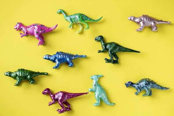黄色表面上的五颜六色的玩具恐龙