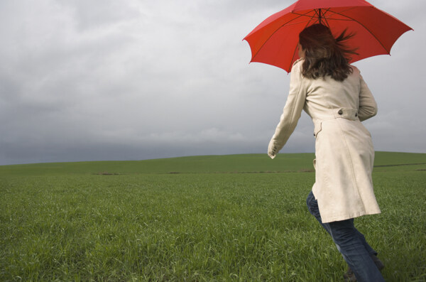 撑着伞在草地上奔跑的女人图片