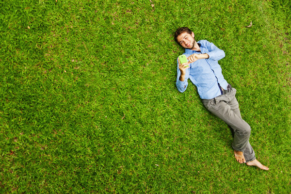 躺在草地上耍手机的男性图片