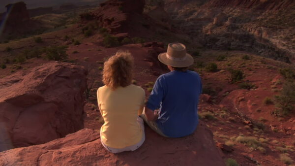 夫妇坐在一个红色的悬崖和欣赏观国会礁国家公园的股票视频视频免费下载